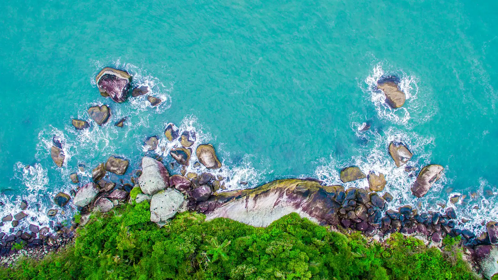 green and gray cliff near body of water in high angle photography