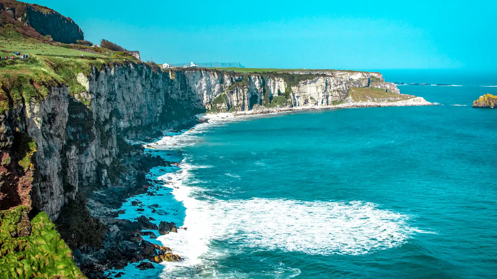 white rock cliff beside body of water'