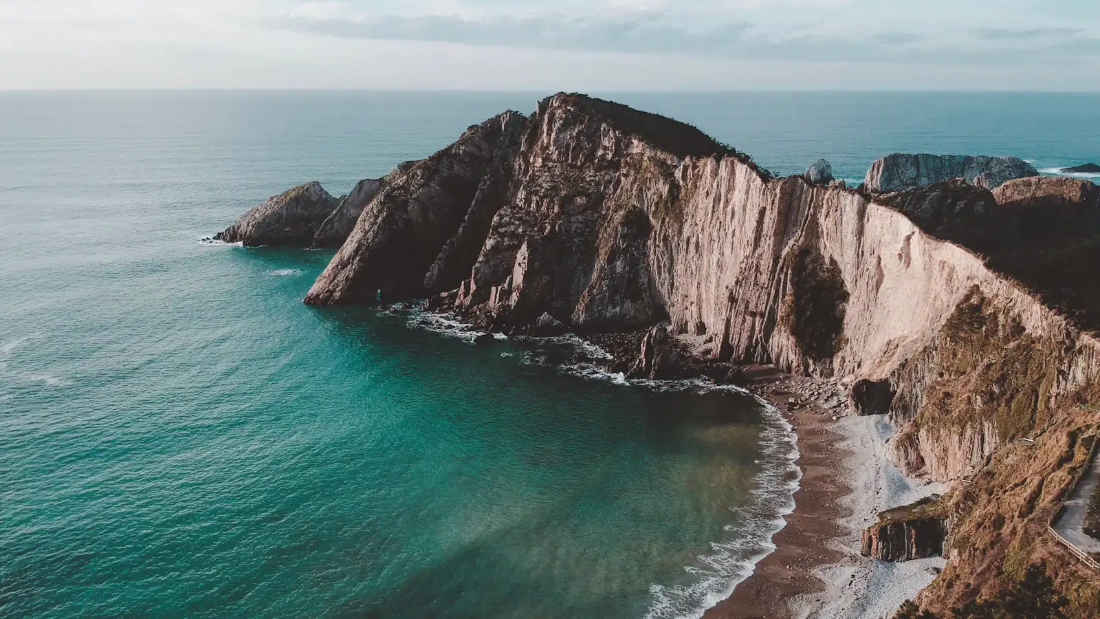 clear blue sea beside mountain