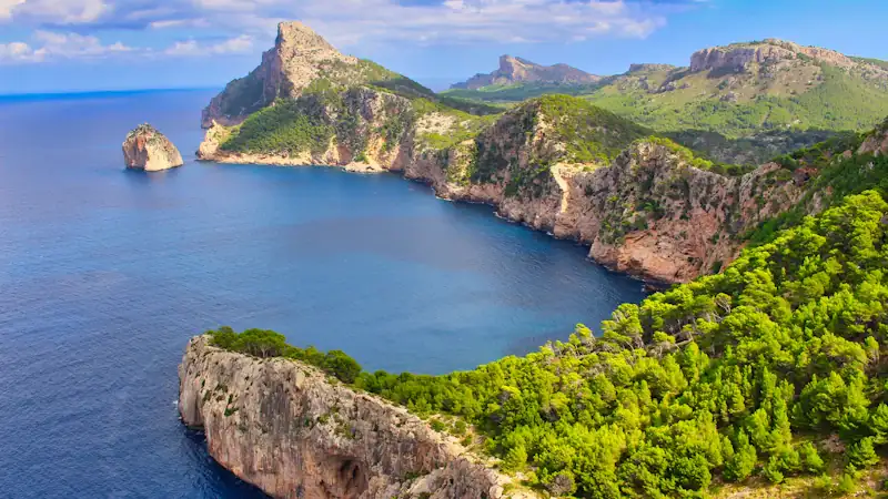 green and brown mountain beside blue sea under blue sky during daytime