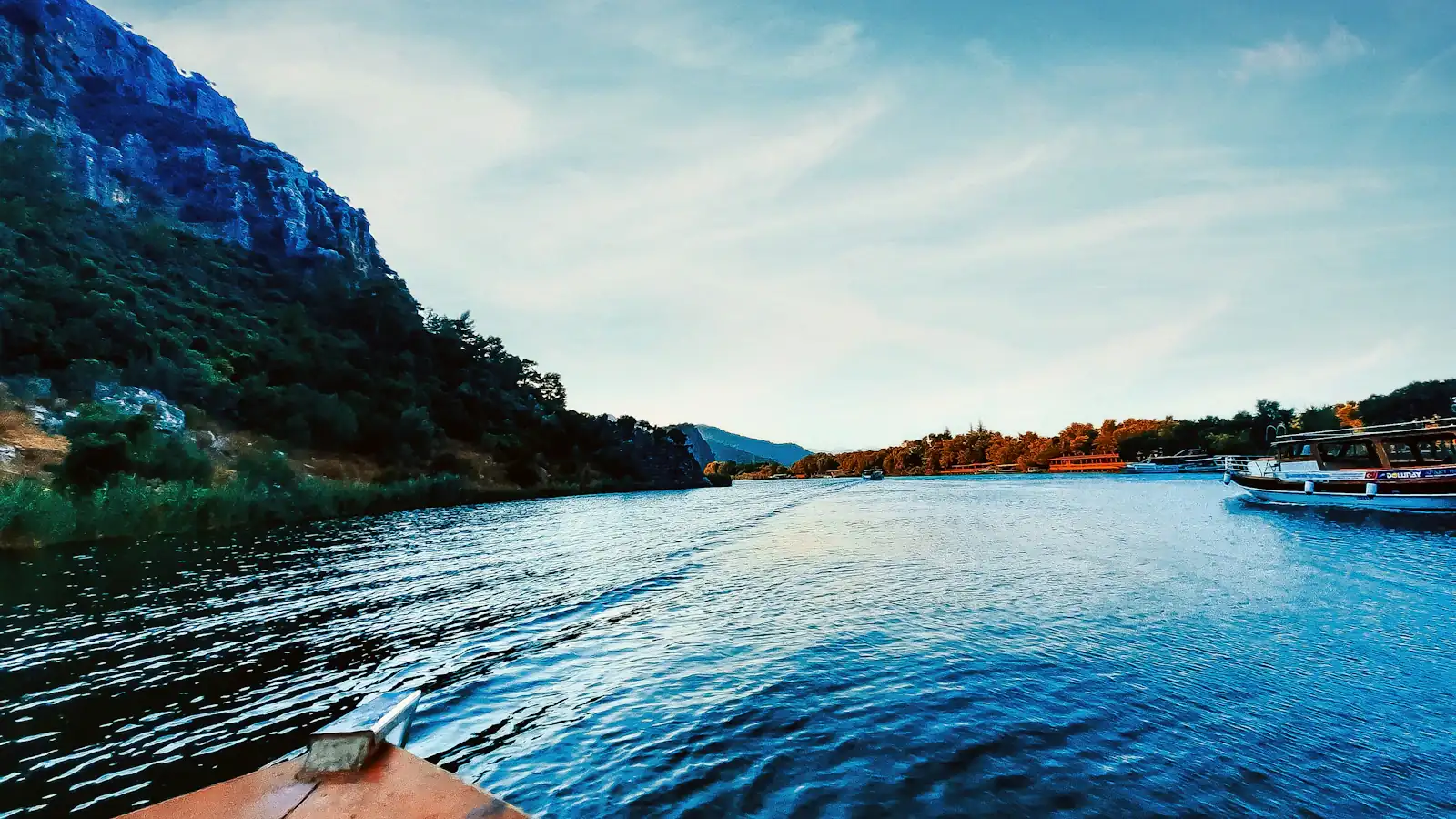 brown canoe on body of water near green mountain during daytime